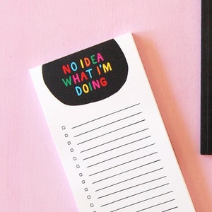May include: Two black notebooks with white lined pages. One notebook has the text "NO IDEA WHAT I'M DOING" in colorful letters. The other notebook has a blank cover.
