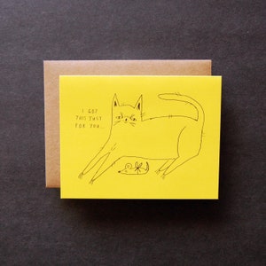 May include: A yellow card with a black line drawing of a cat with a mouse. The text on the card reads "I got this just for you..."