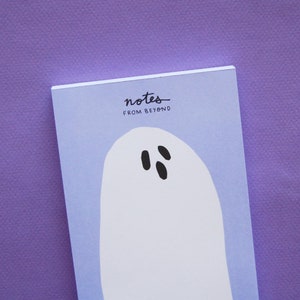May include: A purple notepad with the text "notes from beyond" and a white ghost illustration with black eyes.
