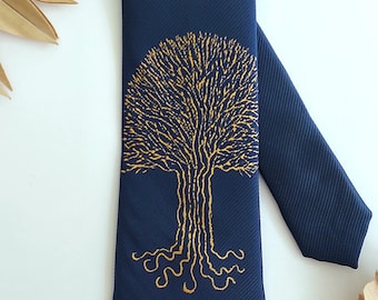 May include: Navy blue necktie featuring a gold tree design. The tree is embroidered with intricate details, showcasing the branches and roots. The tie has a ribbed texture and is made of a smooth fabric. A stylish accessory for formal or casual wear.