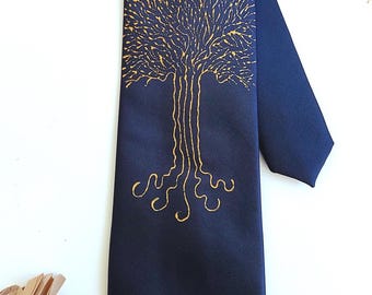 May include: A dark blue silk tie with a gold tree design. The tree has a detailed, intricate design with branches and roots.