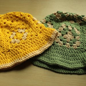 May include: Two crocheted sun hats, one yellow and one green, with a white trim. Both hats have a square pattern.