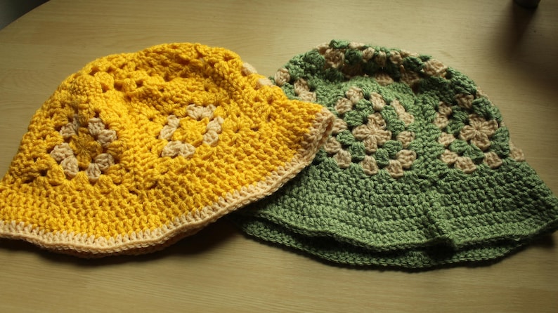 May include: Two crocheted sun hats, one yellow and one green, with a white trim. Both hats have a square pattern.