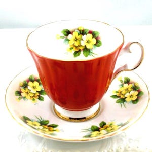Preciosa taza de té y platillo Royal Grafton, delicado diseño de prímula, bordes naranjas, bordes dorados. Porcelana china fabricada en Inglaterra en la década de 1970.
