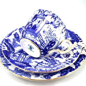 Könnte beinhalten: Ein blaues und weißes Tee-Set mit goldener Verzierung. Das Set zeigt ein japanisch inspiriertes Design mit einer Pagode und floralen Motiven.