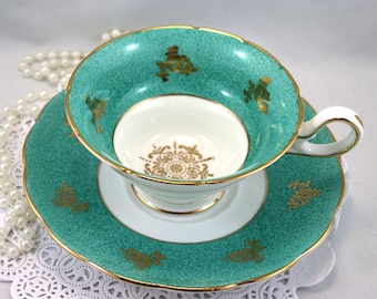 Può includere: Un set da tè in porcellana fine di colore turchese con dettagli dorati e un motivo floreale. La tazza e il piattino hanno un design delicato.
