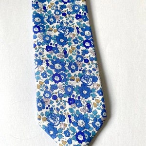 Könnte beinhalten: Eine blaue und weiße Krawatte mit Blumenmuster. Die Krawatte hat einen weißen Hintergrund mit blauen Blumen und Blättern.