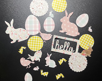 以下が含まれることがあります： ウサギ、鳥、卵、そして「hello」と書かれた看板など、イースターをテーマにした紙の切り抜きを集めたものです。切り抜きは、ギンガムチェック、花柄、水玉模様など、さまざまなパターンでできています。
