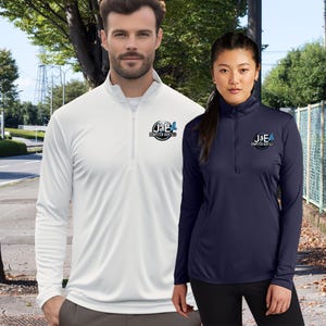 May include: Two people wearing long-sleeved pullovers with a quarter-zip neckline. One is white, the other is navy blue. Both shirts have the logo "J&E Dumpster Rentals" on the left chest. The background shows a street with trees and a fence.