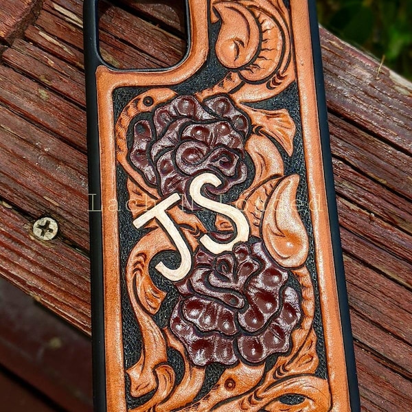 May include: A brown leather phone case with a floral design and the initials "JS" embossed in gold. The case has a black border.