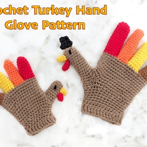 May include: A pair of crocheted turkey hand gloves. The gloves are brown with red, orange, and yellow feathers. The gloves have a turkey head with a beak and wattle on the back of the hand.