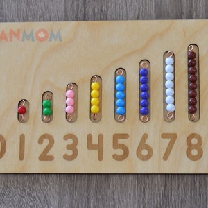 May include: Wooden counting board with rows of colored beads representing numbers 1 through 9. The beads are red, green, pink, yellow, blue, purple, white, brown, and blue. The numbers 0 through 9 are printed below the rows of beads.