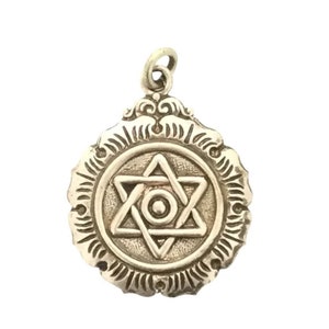 Puede incluir: Pendiente de plata con una estrella de David con un diseño intrincado. El pendiente es redondo y tiene un borde detallado.