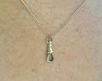 May include: A gold chain necklace with a small gold pendant in the shape of a hook.
