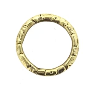 Puede incluir: Un anillo de color dorado con un diseño grabado. El anillo es circular y presenta un patrón repetido de pequeñas formas estilizadas de flores o hojas alrededor de su banda. El anillo está sobre un fondo blanco.