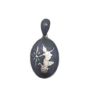 May include: A silver pendant with a black oval background featuring a silver silhouette of a dancing figure with a halo and a raised arm holding a lightning bolt.