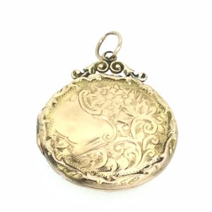 May include: A gold locket with an ornate floral design. The locket has a hinged lid and a loop for attaching a chain.