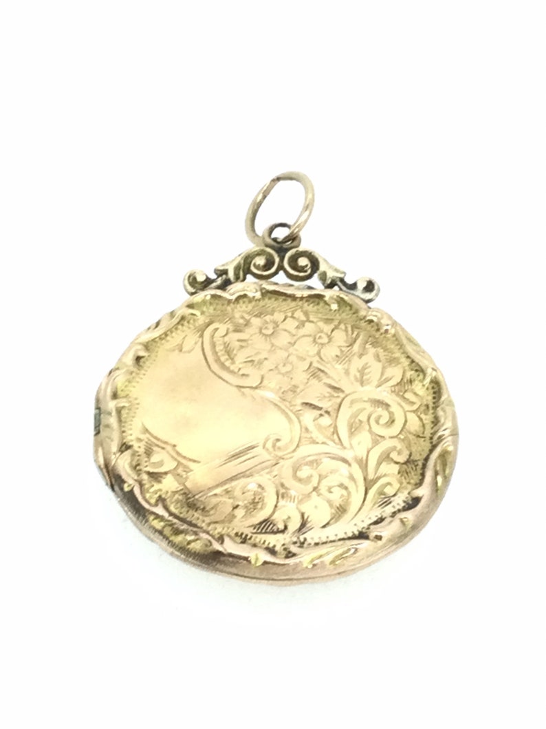May include: A gold locket with an ornate floral design. The locket has a hinged lid and a loop for attaching a chain.
