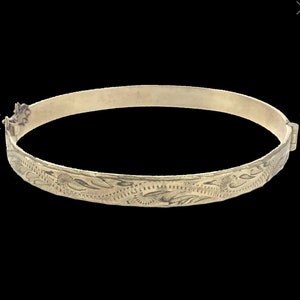 May include: A gold bangle bracelet with a delicate floral design.