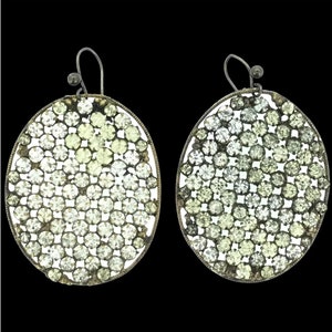 Może przedstawiać: Para srebrnych, owalnych kolczyków z wzorem z małych, przezroczystych cyrkonii ułożonych w okrągły wzór.