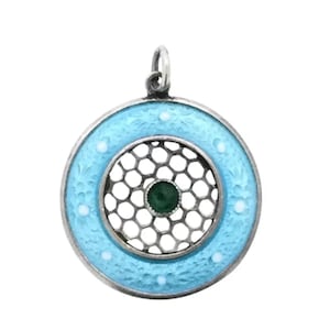 May include: A silver pendant with a blue enamel circle and a green stone in the center. The circle has a delicate, openwork design.