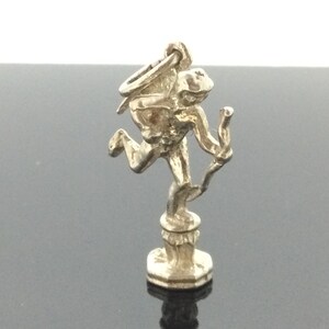 May include: Silver charm of a winged cupid holding an arrow, standing on a pedestal.