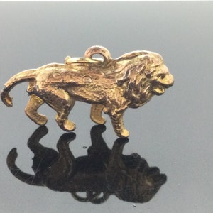 以下が含まれることがあります： 金色のライオンのチャームペンダント。ライオンは4本足で立っており、頭は横に傾いています。チャームの上部には、チェーンやブレスレットに取り付けるためのループが付いています。