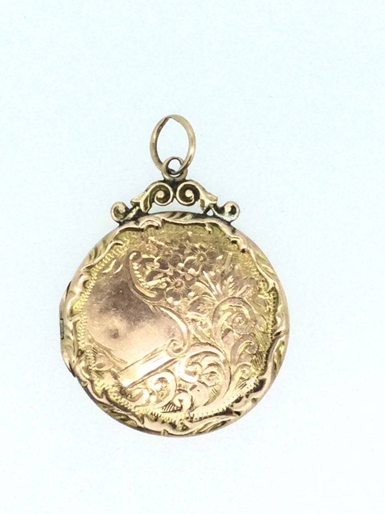 May include: A gold locket with an ornate floral design. The locket has a hinged lid and a loop for attaching a chain.