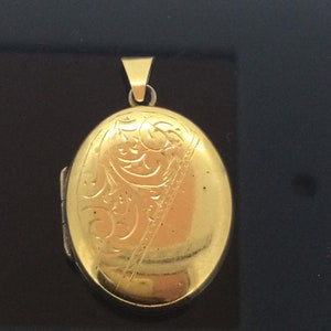 May include: A gold oval locket with an engraved floral design.
