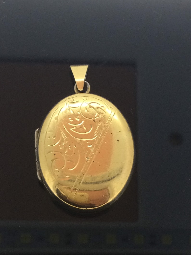 May include: A gold oval locket with an engraved floral design.