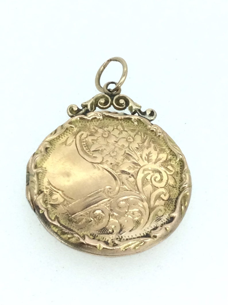 May include: A gold locket with an ornate floral design. The locket has a hinged lid and a loop for attaching a chain.