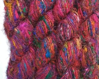Könnte beinhalten: Drei Knäuel bunter Wolle mit einem Mix aus roten, rosa, blauen, grünen und gelben Fäden. Die Wolle ist aus Seide und hat eine flauschige Textur.