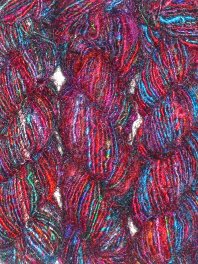 May include: Close-up of a skein of yarn with a mix of red, blue, and purple fibers. The yarn is soft and fluffy, and it has a slightly iridescent sheen.