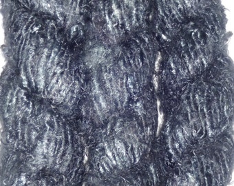 May include: Three bundles of dark gray, fluffy yarn. The yarn is tightly packed and has a slightly shiny appearance.