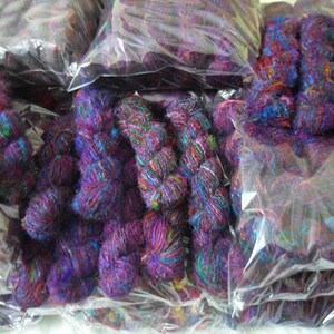 Peut inclure: Plusieurs paquets de fil color&eacute; dans des tons de violet, bleu et vert sont emball&eacute;s dans des sacs en plastique transparent. Le fil est fait d'un mat&eacute;riau doux et duveteux et est parfait pour le tricot ou le crochet.