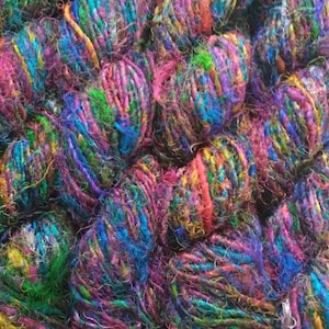 May include: A close-up of a pile of colorful yarn balls. The yarn is made of a variety of materials, including silk, cotton, and wool. The colors are bright and vibrant, and the yarn is soft and fluffy.