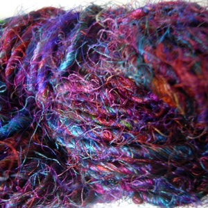 Peut inclure: Un gros plan d'une pelote de fil avec un m&eacute;lange de couleurs violettes, bleues et brunes. Le fil est tr&egrave;s fin et a une texture duveteuse.