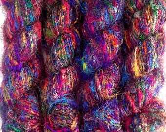 Könnte beinhalten: Vier Knäuel bunter Wolle mit einer Mischung aus Texturen, darunter Seide und Wolle. Die Wolle ist eine Mischung aus Lila, Blau, Rot, Grün und Gelb.