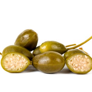 a pile of green fruit sitting on top of a white table