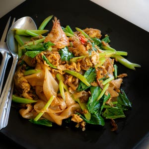 a black plate topped with noodles and vegetables