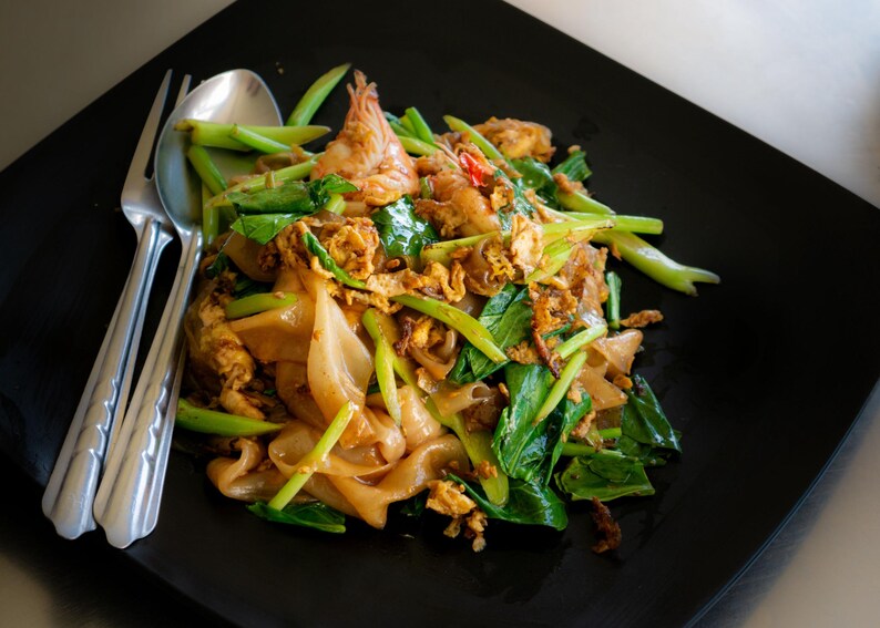 a black plate topped with noodles and vegetables
