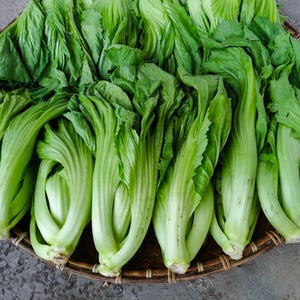 a basket filled with lots of green vegetables