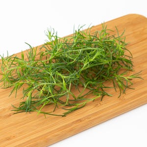 a pile of green grass sitting on top of a wooden cutting board
