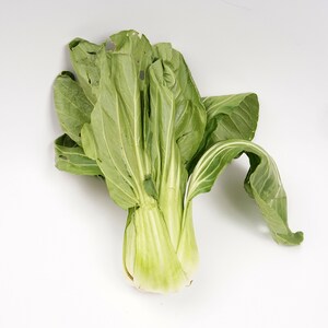 a group of green leafy vegetables on a white surface