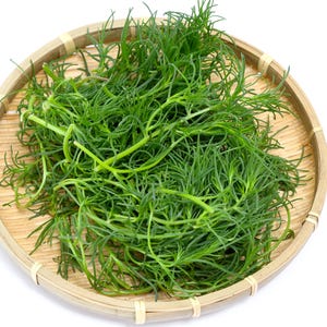 a wooden bowl filled with green grass on top of a white table