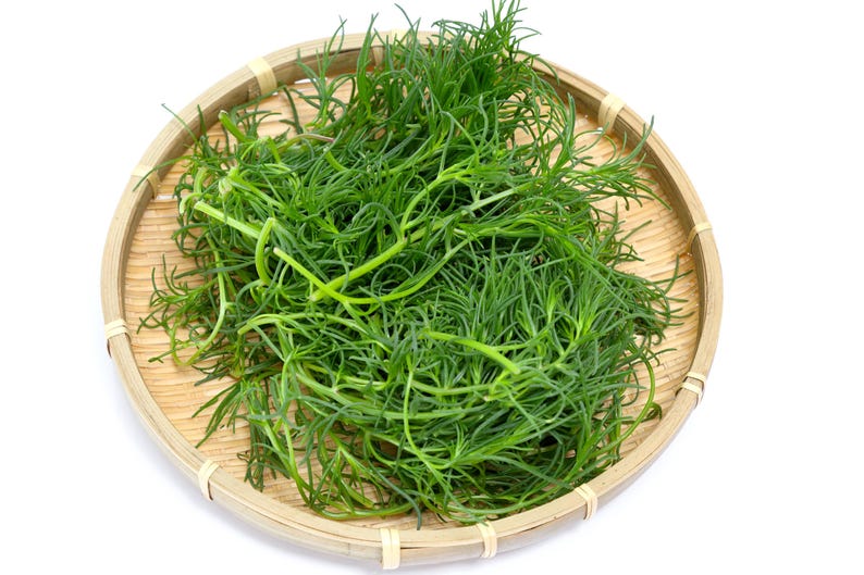a wooden bowl filled with green grass on top of a white table