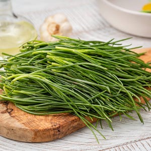a bunch of green grass sitting on top of a wooden cutting board