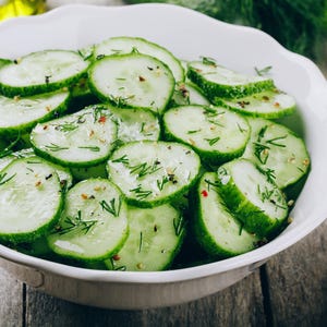 a bowl of sliced cucumbers on a wooden table