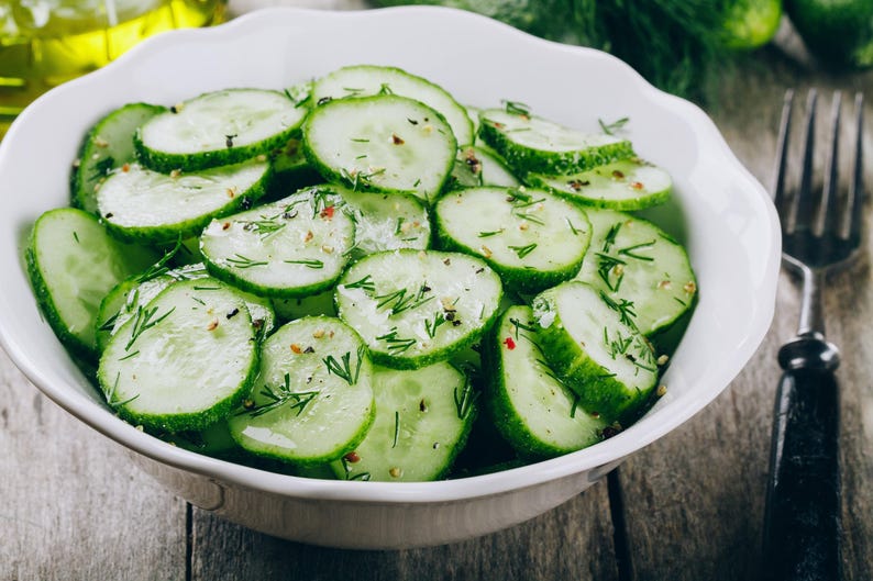 a bowl of sliced cucumbers on a wooden table