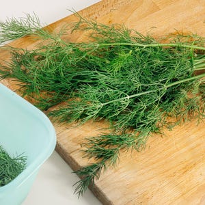 a wooden cutting board topped with green herbs